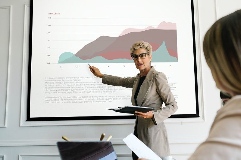 Uma mulher apontando para uma apresentação com um gráfico.