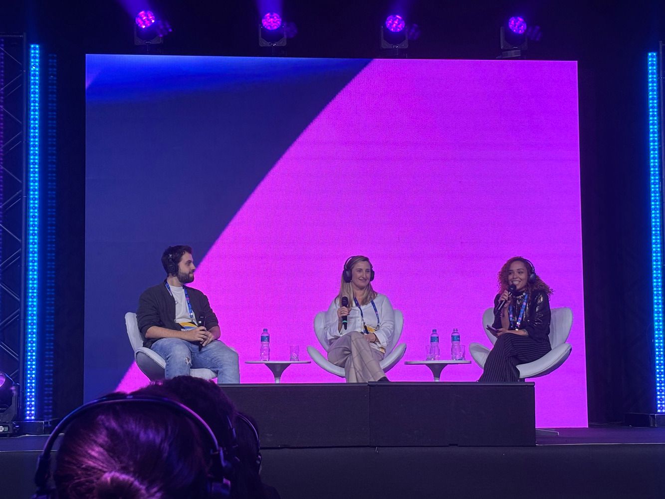 Painel sobre cultura, com um speaker homem e duas mulheres no palco