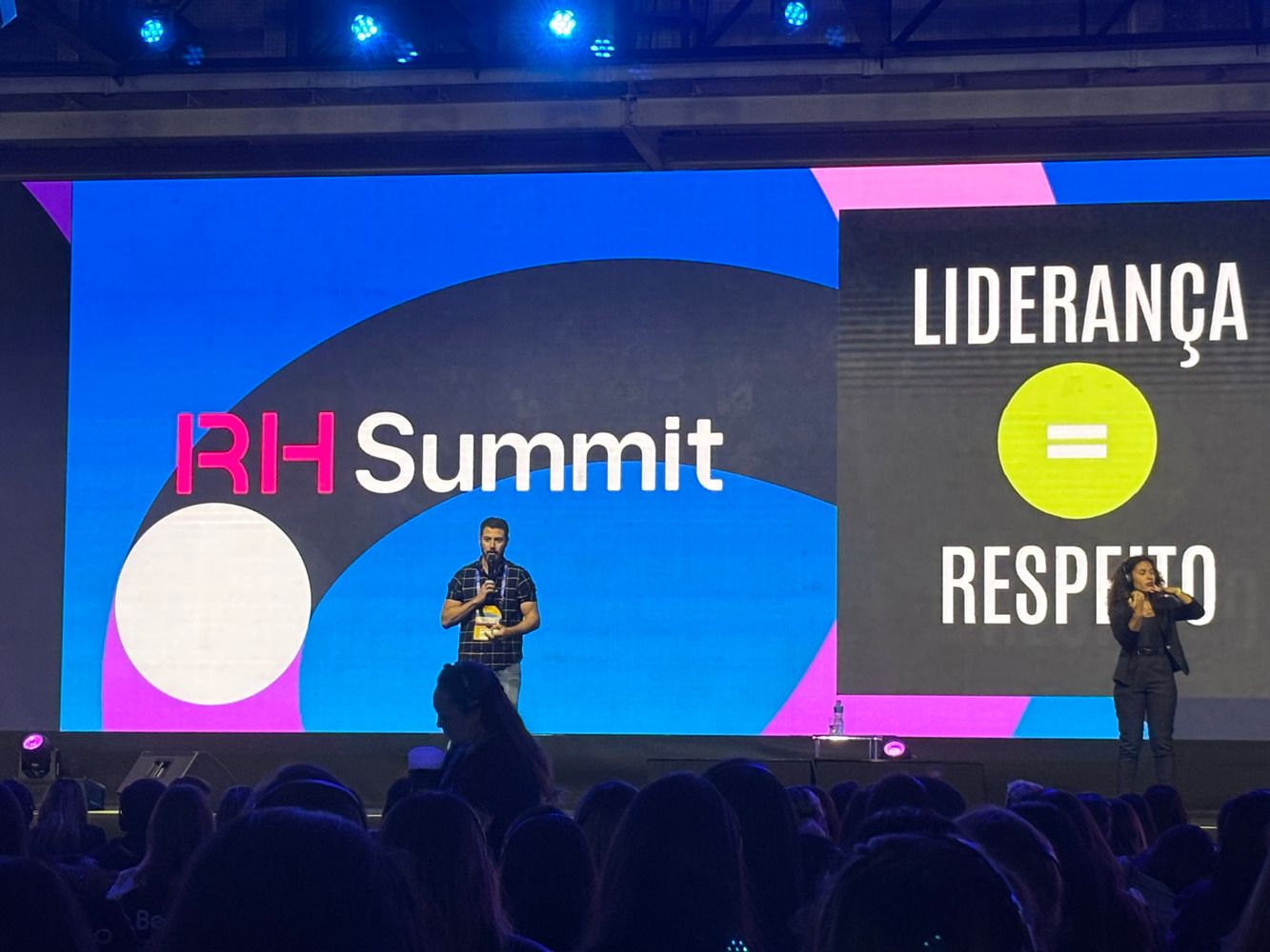 Homem palestrando em palco de evento