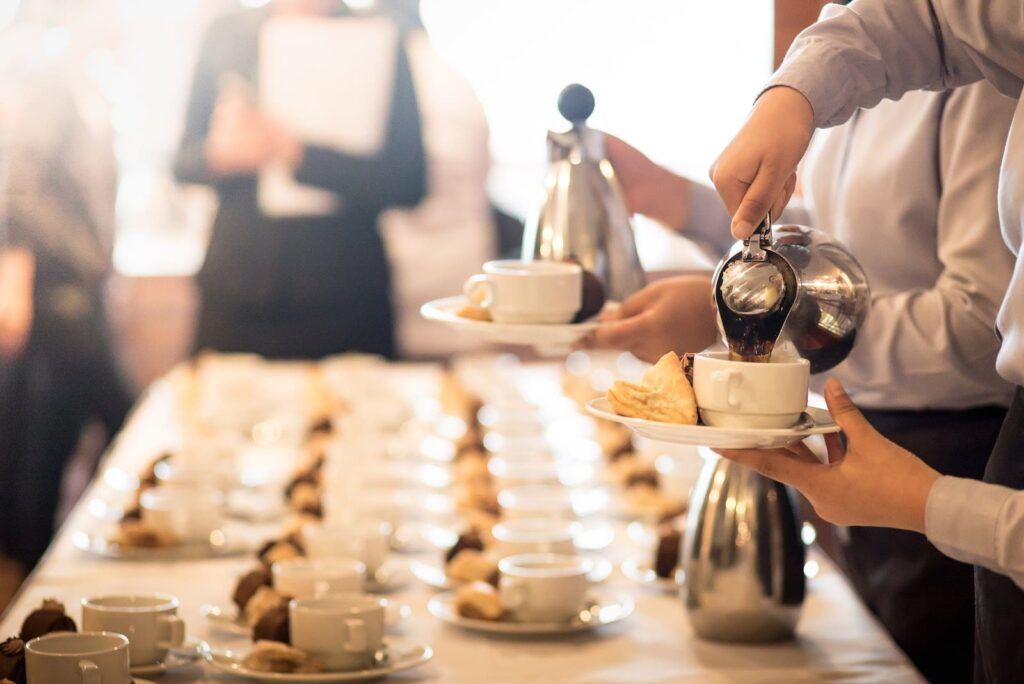 Pessoas servindo café e chá em um coffee break corporativo.