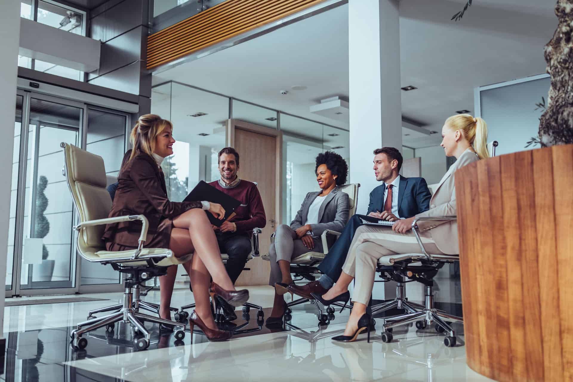 Grupo de 5 pessoas sentadas conversando sobre trabalho. 